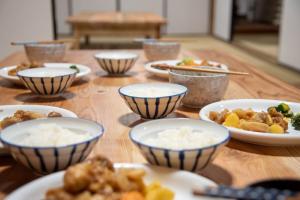 a wooden table with bowls of food on it at Worcation base Kaminyu Yamane House - Vacation STAY 03960v in Nagahama +7 photos