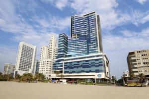 a tall building with blue windows in front of a city at Hotel InterContinental Cartagena by IHG in Cartagena de Indias