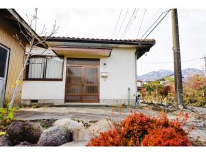 a white house with a brown door and some rocks at Second House Nikko - Vacation STAY 13408 in Nikko