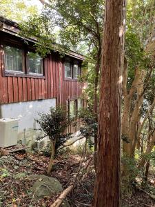 une maison rouge avec un arbre devant elle dans l'établissement Yamagoya limelight - Vacation STAY 79313v, à Okawa