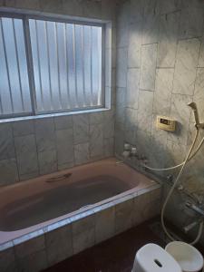 a bathroom with a pink bath tub and a toilet at Curfew by midnight Guesthouse Tosa Hanare - Vacation STAY 14262 in Kochi