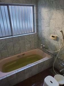 a bathroom with a tub with a toilet and a window at Curfew by midnight Guesthouse Tosa Hanare - Vacation STAY 14263 in Kochi