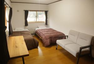 a bedroom with a bed and a couch and a chair at Active House Ryuo - Vacation STAY 04019v in Shimotakai