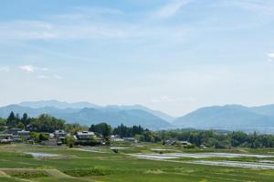 a field with houses and mountains in the background at Satoyama villa DEN - Vacation STAY 17844 in Matsumoto