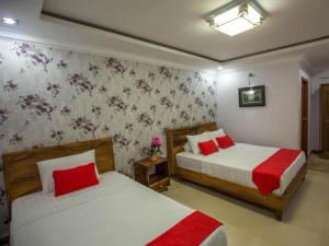 Un dormitorio con dos camas con sábanas rojas y blancas. en Alice Villa Hotel, en Takeo