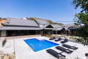 ein Haus mit einem Pool und Liegestühlen in der Unterkunft Wellis Villa Awaji - Vacation STAY 15883 in Ikuta