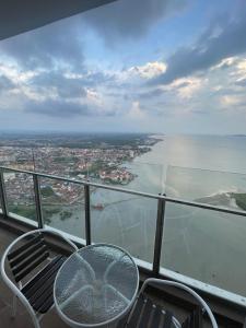 a table and chairs on a balcony with a view of the water at Silverscape Residence in Melaka