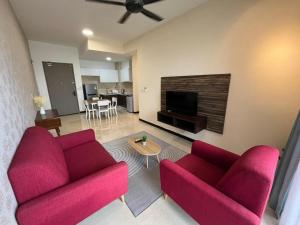 a living room with two red couches and a tv at 2 Bedrooms Seaview Apartment in Silverscape Residence in Malacca