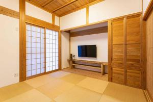 ein Wohnzimmer mit einem TV und Holzschränken in der Unterkunft Private resort Hibiki no Yado & Mori - Vacation STAY 85304v in Sato-moriya