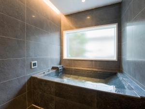 ein Badezimmer mit einer großen Badewanne und einem Fenster in der Unterkunft Rakuten STAY VILLA Yatsugatake - 104 Family Room Pets Friendly - in Hokuto