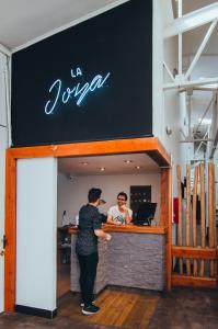 two people standing at the counter of a restaurant at La Joya Hostel in Valparaíso