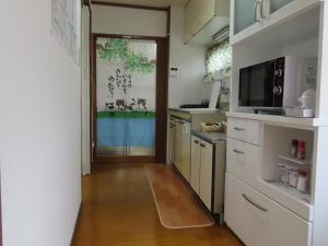 a kitchen with a door leading to a kitchen with white cabinets at SORAMACHI - Vacation STAY 14338 in Takayama +20 photos