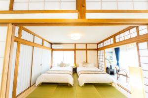 two beds in a room with windows at Ａｗａｊｉ Ｓｅａｓｉｄｅ Ｖｉｌｌａ ｉｎ Ｇｏｓｈｉｋｉ - Vacation STAY 98416v in Sumoto