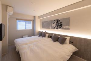 a bedroom with a large white bed with pillows at ONE WORLD Sakaisuji Honmachi - Vacation STAY 09657v in Osaka +37 photos