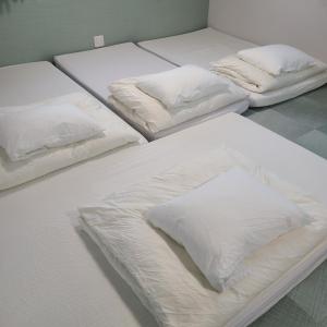 three beds with white sheets and pillows in a room at Fluctus - Vacation STAY 16974v in Hitachi