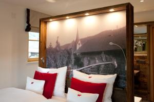 Un dormitorio con una cama con almohadas rojas y blancas. en Dorfhaus Chalets, en Oberstaufen