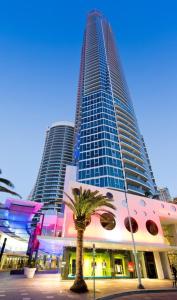 Entire 2 bdrm apt in Hilton Surfers Paradise -7 في غولد كوست: مبنى طويل يوجد أمامه شجرة نخيل
