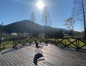 a chair on a wooden deck with the sun behind it at Log Cottage Yamanohiroba - Vacation STAY 40692v in Shiso +7 photos