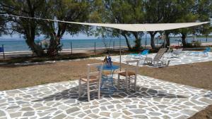 uma mesa e cadeiras debaixo de um guarda-sol branco na praia em Villa Zoi em Thrónion