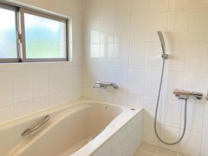 a white bathroom with a tub and a window at kukulu island - Vacation STAY 37864v in Kouri