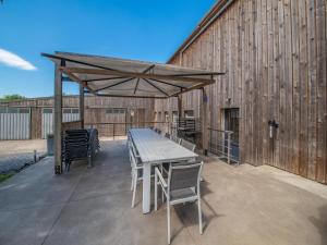 une table et des chaises sous un auvent en bois sur la terrasse dans l'établissement Luxurious house with sauna in Bastogne, à Bastogne