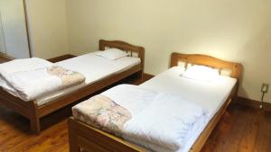 two beds in a room with wooden floors at Tabino Camping Base Kami Yuland - Vacation STAY 52575v in Osaki