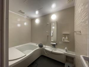 a bathroom with a tub and a sink and a mirror at IHOKI BASE - Vacation STAY 57543v in Kumano
