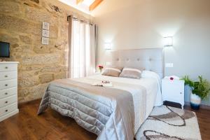 Un dormitorio con una gran cama blanca y una pared de piedra. en A Cantaruxa Maruxa Turismo Rural, en Mondariz