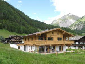 a large wooden building with mountains in the background at Großglockner Goldried Chalet in Kals am Großglockner