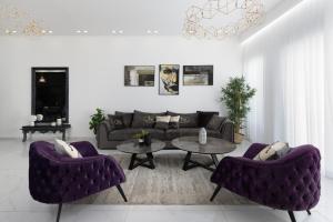 ein Wohnzimmer mit lila Sofas und einem Tisch in der Unterkunft ים סוף - דירת גן מושלמת עם בריכה פרטית למשפחות באילת in Eilat