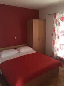 a bedroom with a large bed with a red blanket at Apartments & rooms Ana Sukosan in Sukošan