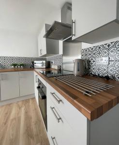 a kitchen with white cabinets and a wooden counter top at High Street Apartment in Garstang +9 photos