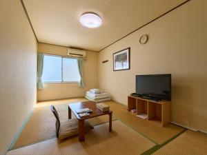 a living room with a television and a table at Tabist Business Hotel Teramoto in Chita