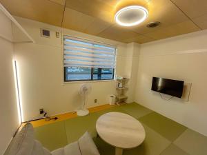 a living room with a table and a tv and a window at しばママのお宿 ShibaMamas Casual Hotel in Zaō Onsen