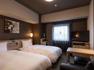 Una habitación de hotel con dos camas y un televisor. en Hotel Route Inn Kanonji, 