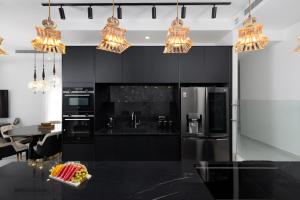 eine Küche mit schwarzen Schränken und Kronleuchtern in der Unterkunft ים סוף - דירת גן מושלמת עם בריכה פרטית למשפחות באילת in Eilat