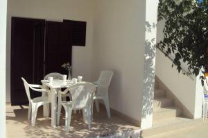 a white table and chairs sitting next to a building at Apartments Marko in Vrsi
