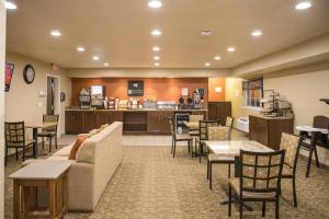 un salon avec un canapé, des tables et des chaises dans l'établissement MainStay Suites Coralville - Iowa City, à Coralville