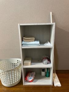 ein weißes Regal mit einigen Handtüchern und einem Korb in der Unterkunft Chambord Kyomachi 205 - Vacation STAY 69095v in Kumamoto