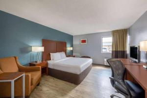 a hotel room with a bed and a couch and a television at Travelodge by Wyndham Brooklyn Center in Minneapolis