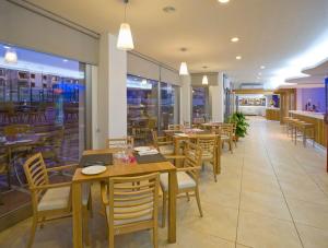 uma sala de jantar com mesas e cadeiras de madeira num restaurante em Bon Sol Prestige - AB Group em Playa d'en Bossa