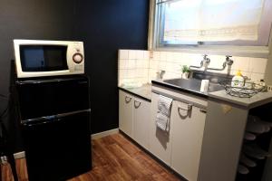 a small kitchen with a microwave and a sink at Daiichi Mitsumi Corporation - Vacation STAY 15348 in Musashino