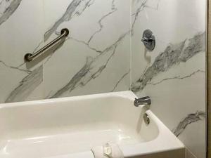 a white bath tub in a bathroom with marble walls at Suburban Studios Columbia - Harbison in Columbia +13 photos