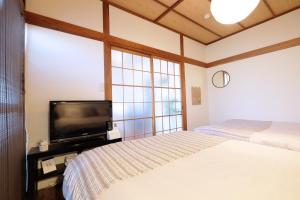 ein Schlafzimmer mit zwei Betten und einem Flachbildfernseher in der Unterkunft Daiichi Mitsumi Corporation - Vacation STAY 15355 in Musashino