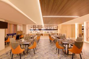 a restaurant with tables and chairs and a kitchen at Keys Lite by Lemon Tree Hotels, Krishna, Vijayawada in Vijayawāda