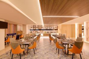 a restaurant with tables and chairs and a kitchen at Keys Lite by Lemon Tree Hotels, Krishna, Vijayawada in Vijayawāda