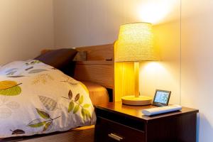 eine Lampe auf einem Nachttisch neben einem Bett in der Unterkunft CoCoSakura - Vacation STAY 94917v in Miyanoshita