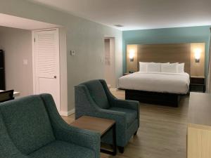 a hotel room with a bed and two chairs at MainStay Suites Springfield South - Battlefield Rd in Springfield +56 photos