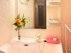 a bathroom sink with a vase of flowers and a mirror at GuestHouse FUKUTOMI - Vacation STAY 95726v in Makishimachi
