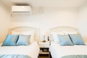 two beds with blue pillows in a bedroom at Oceanfront Villa Hale Kahakai - Vacation STAY 52334v in Miura